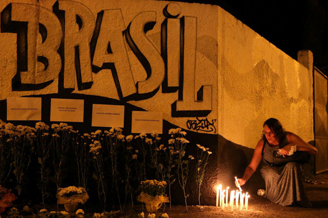 Uma mulher acende velas durante homenagem às vítimas do tiroteio na escola Raul Brasil em Suzano, São Paulo. Foto: Agência Brasil